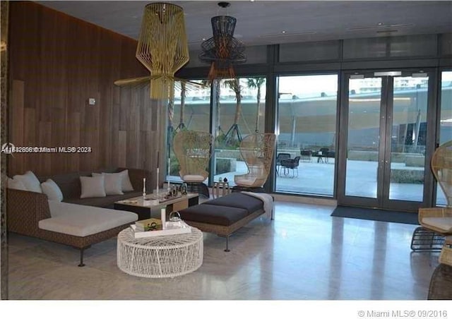 living room with plenty of natural light, french doors, and wooden walls