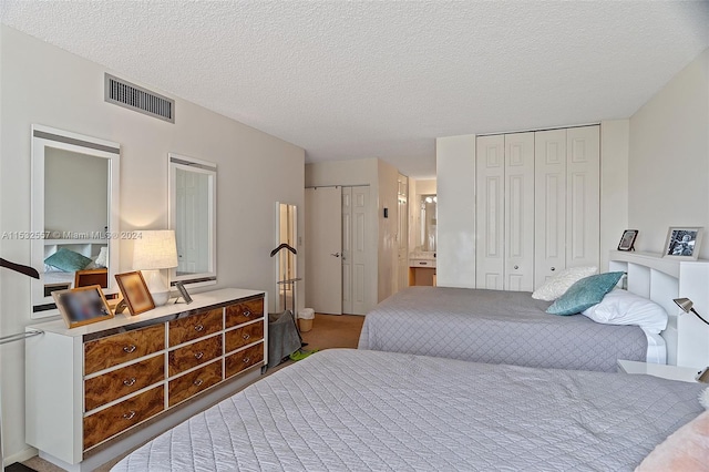 bedroom featuring carpet, multiple closets, connected bathroom, and a textured ceiling