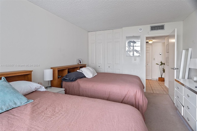 carpeted bedroom featuring a closet and a textured ceiling