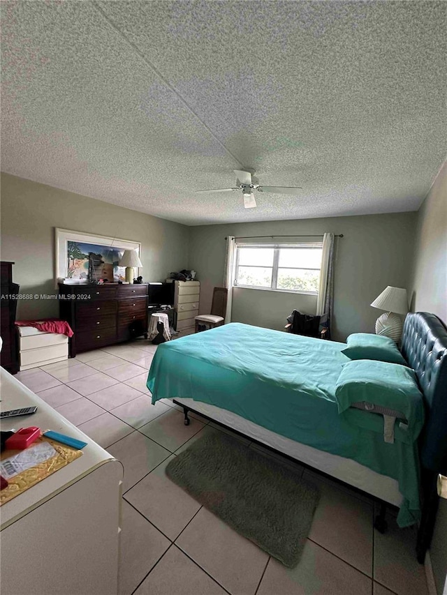 bedroom with ceiling fan, tile patterned flooring, and a textured ceiling
