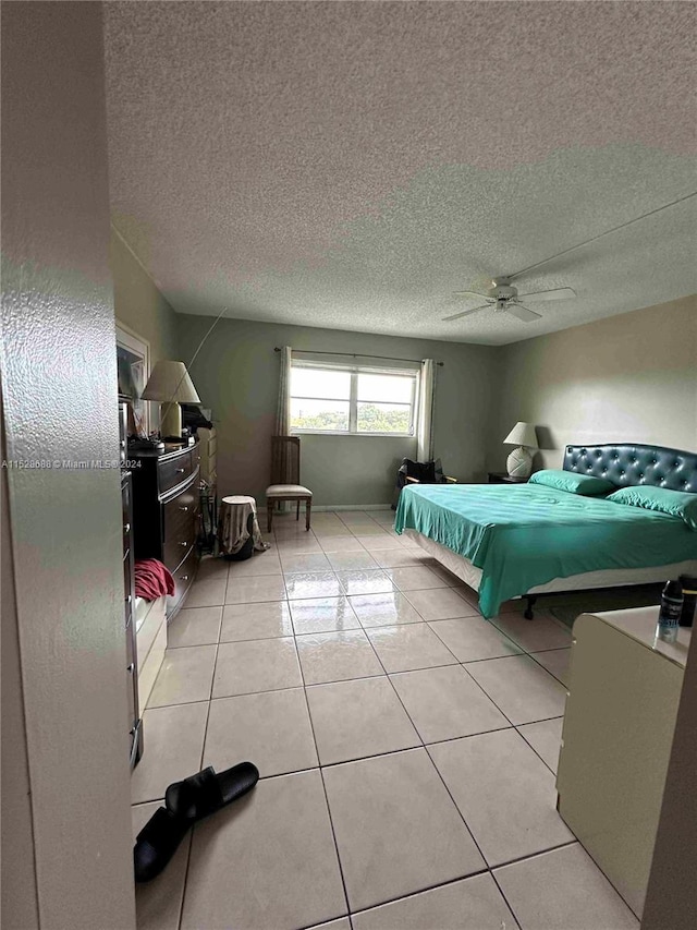 bedroom featuring ceiling fan, a textured ceiling, and light tile patterned floors