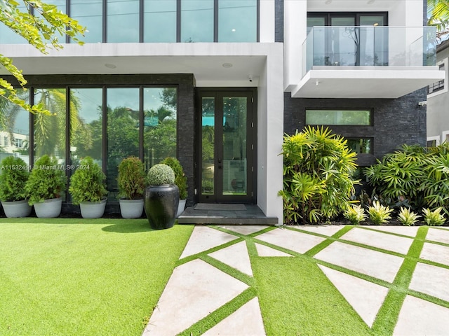 entrance to property with a balcony, french doors, and a yard