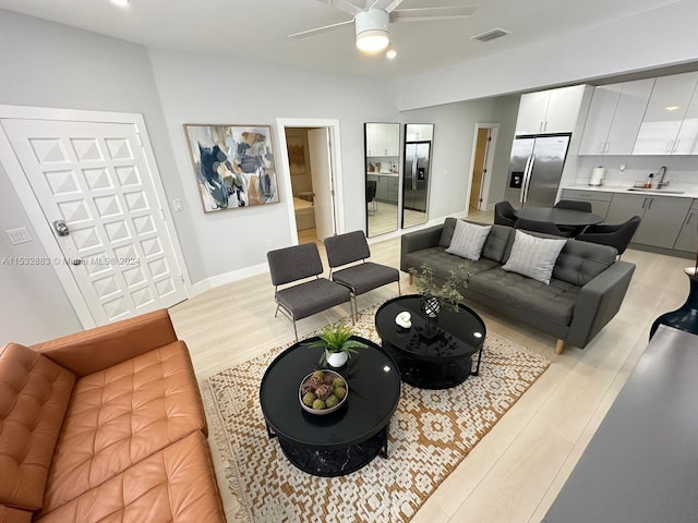 living room featuring ceiling fan, sink, and light hardwood / wood-style flooring