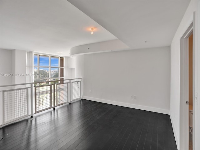 empty room featuring floor to ceiling windows and dark wood-type flooring