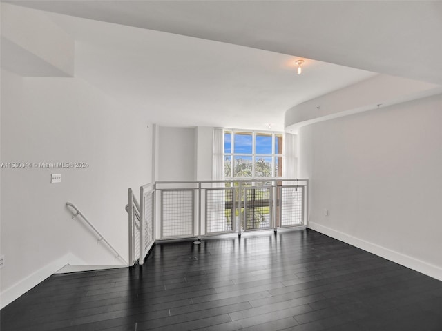 empty room with dark hardwood / wood-style flooring and a wall of windows