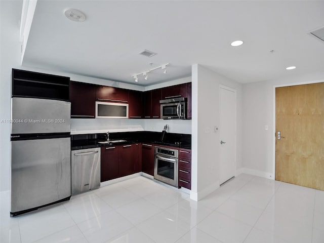 kitchen featuring stainless steel appliances, track lighting, light tile floors, and sink