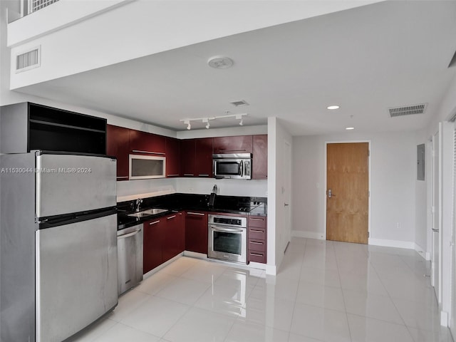 kitchen featuring rail lighting, stainless steel appliances, sink, and light tile floors