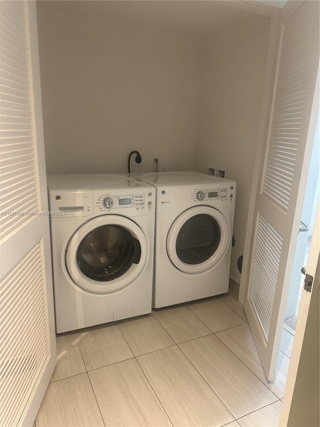 washroom with washer and clothes dryer, light tile flooring, and hookup for a washing machine