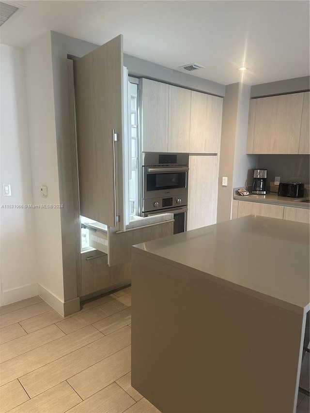 kitchen with double oven and light brown cabinetry