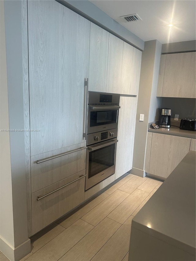 kitchen featuring double oven, light hardwood / wood-style floors, and light brown cabinetry