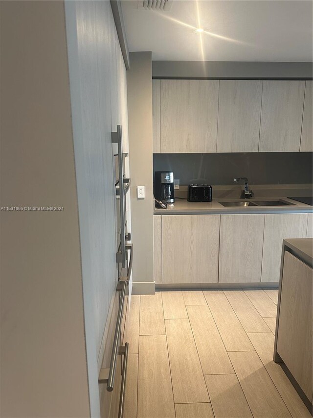 kitchen featuring light brown cabinetry, sink, and light wood-type flooring