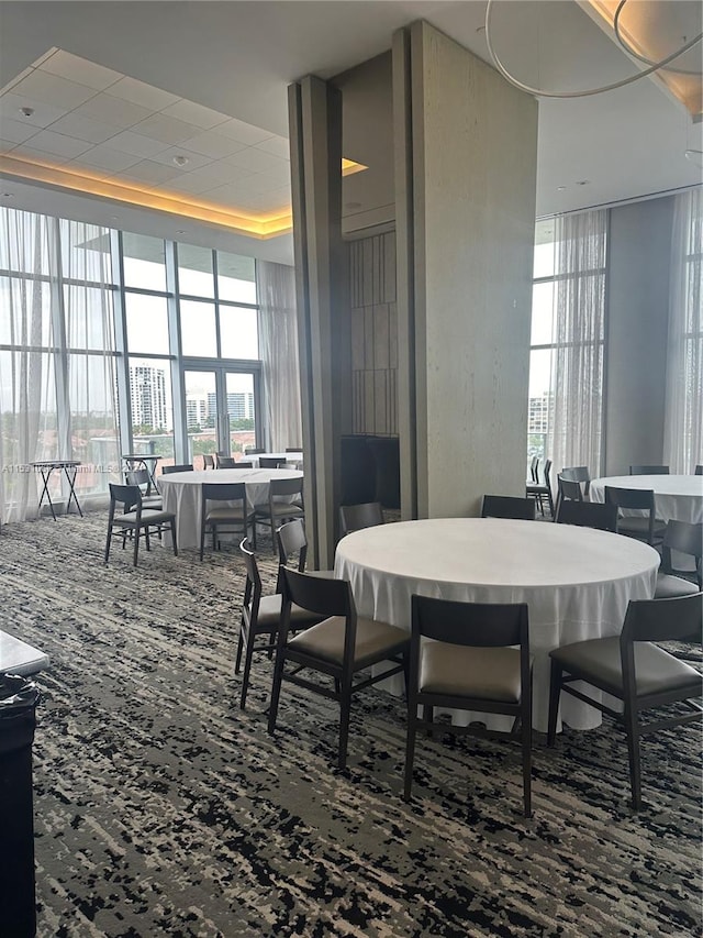 carpeted dining area featuring expansive windows and a towering ceiling