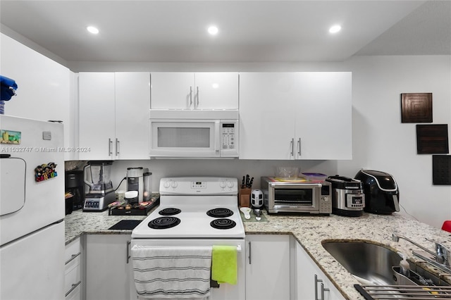 kitchen featuring sink, white appliances, light stone countertops, and white cabinets