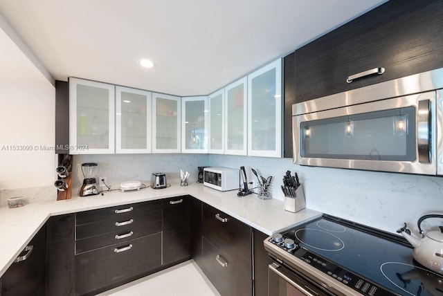 kitchen featuring dark brown cabinetry, light stone countertops, white cabinets, and stove