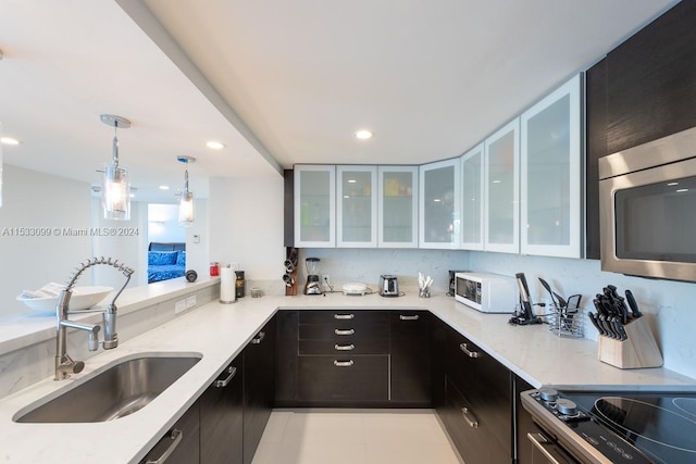 kitchen with light stone countertops, decorative light fixtures, stove, light tile floors, and sink