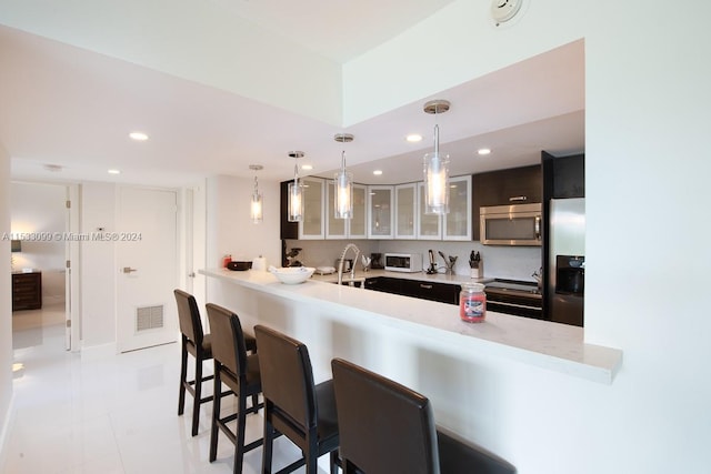 kitchen featuring decorative light fixtures, kitchen peninsula, a kitchen breakfast bar, appliances with stainless steel finishes, and light tile floors