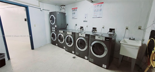 clothes washing area with stacked washer / dryer, washer hookup, light tile floors, sink, and washer and clothes dryer