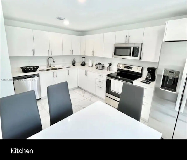 kitchen featuring white cabinetry, light tile flooring, appliances with stainless steel finishes, and sink