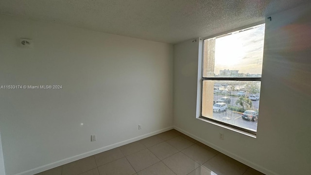 empty room with light tile flooring and a textured ceiling