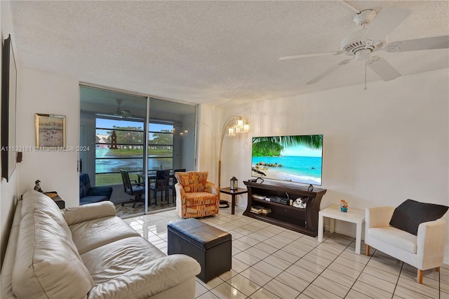 tiled living room with a water view, a textured ceiling, and ceiling fan