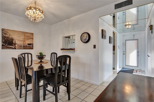 tiled dining area with a chandelier and a textured ceiling