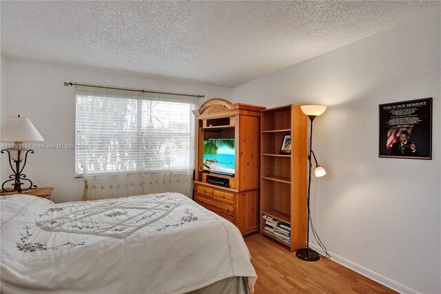 bedroom featuring light hardwood / wood-style flooring and a textured ceiling