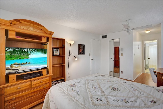 bedroom with a textured ceiling, a closet, ceiling fan, and light hardwood / wood-style flooring