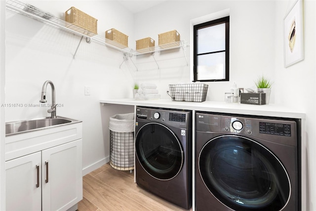 laundry room featuring cabinets, washer and clothes dryer, sink, and light hardwood / wood-style floors