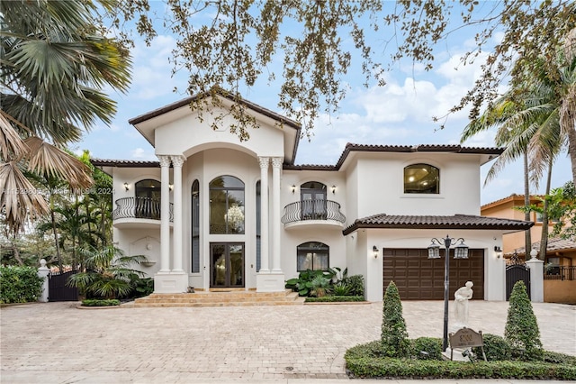 mediterranean / spanish-style home with a balcony, french doors, and a garage