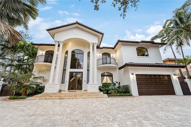 mediterranean / spanish-style home with a balcony, a garage, and french doors