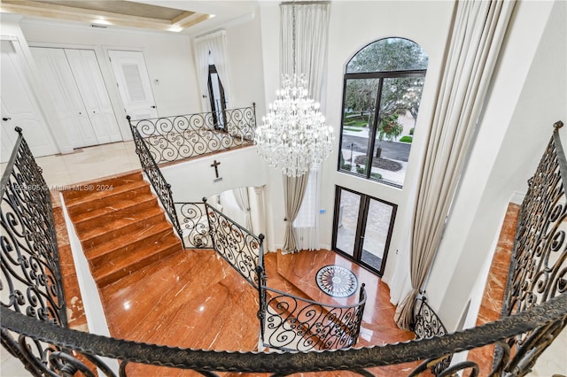 interior space featuring a raised ceiling, french doors, a chandelier, and a towering ceiling