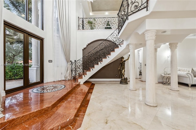 entrance foyer with ornate columns, french doors, light tile floors, and a high ceiling