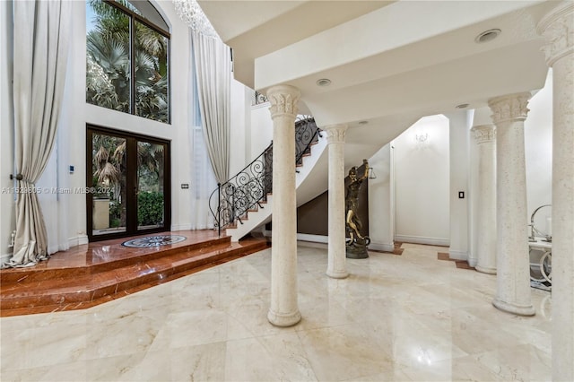 tiled entryway with a high ceiling, ornate columns, and french doors