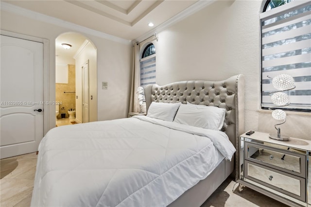 bedroom featuring crown molding, ensuite bath, and a tray ceiling