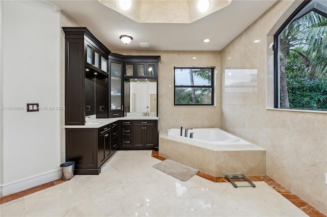 bathroom with plenty of natural light, tiled bath, vanity, and tile flooring