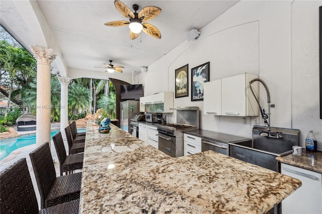 exterior space featuring an outdoor kitchen, ceiling fan, and sink