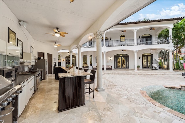 view of patio / terrace featuring a balcony, french doors, an outdoor kitchen, and ceiling fan