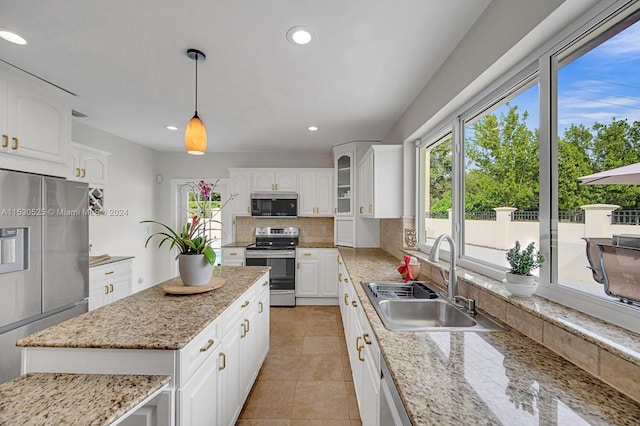 kitchen featuring appliances with stainless steel finishes, tasteful backsplash, white cabinetry, sink, and hanging light fixtures