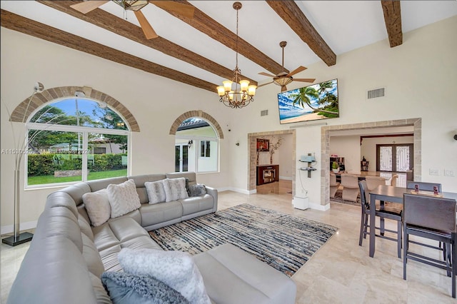 living room featuring a healthy amount of sunlight, beam ceiling, ceiling fan with notable chandelier, and a high ceiling