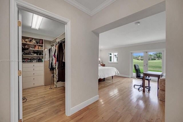 hallway featuring built in shelves, light hardwood / wood-style flooring, and ornamental molding