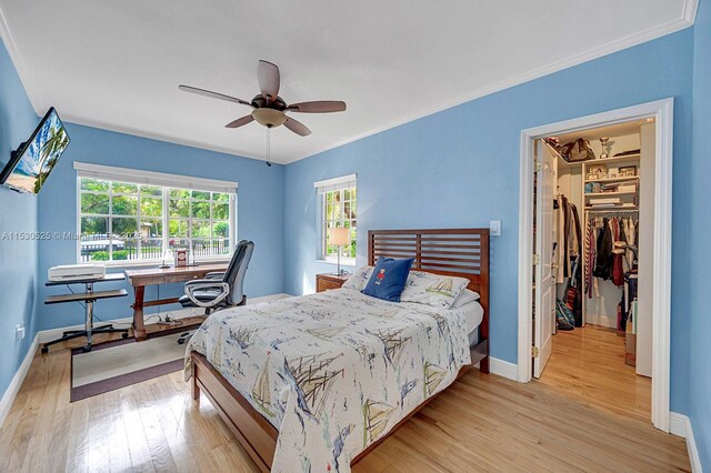 bedroom featuring hardwood / wood-style floors, ornamental molding, a chandelier, and multiple closets