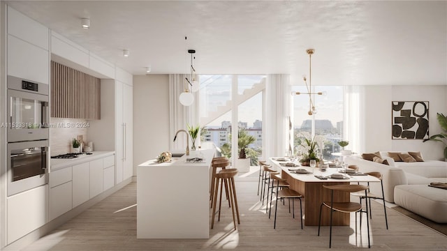 kitchen with a kitchen bar, decorative light fixtures, and an island with sink