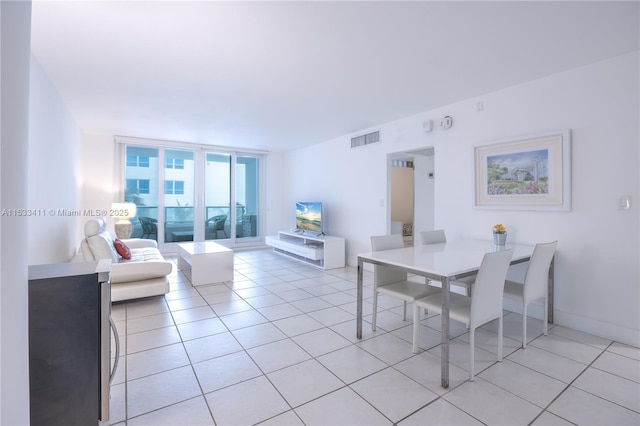 dining area featuring light tile patterned floors, baseboards, visible vents, and a wall of windows