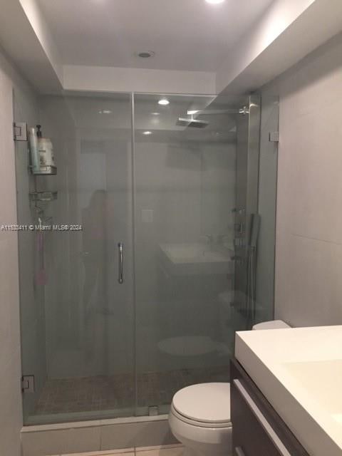 bathroom with toilet, an enclosed shower, and vanity