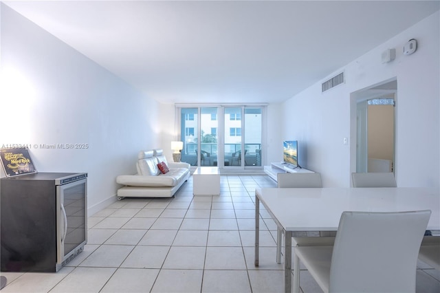 living room with a wall of windows, visible vents, baseboards, and light tile patterned floors