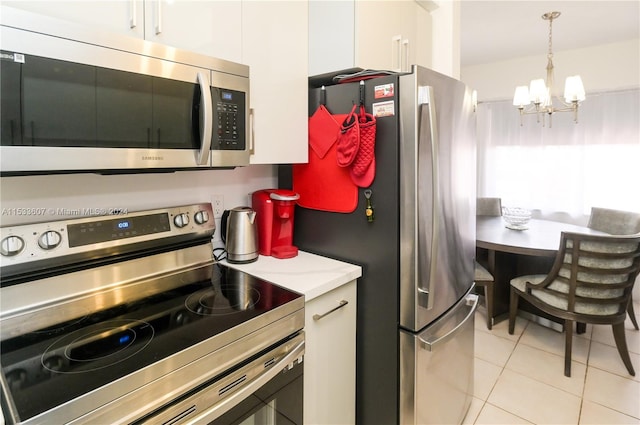 kitchen featuring hanging light fixtures, stainless steel appliances, light tile floors, white cabinets, and a chandelier