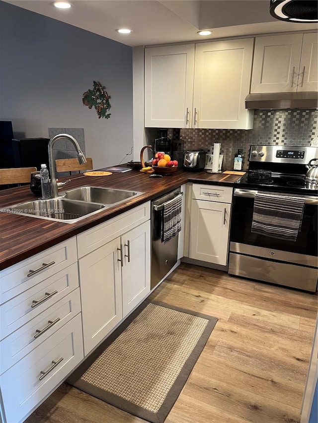 kitchen featuring light hardwood / wood-style floors, wood counters, appliances with stainless steel finishes, sink, and tasteful backsplash