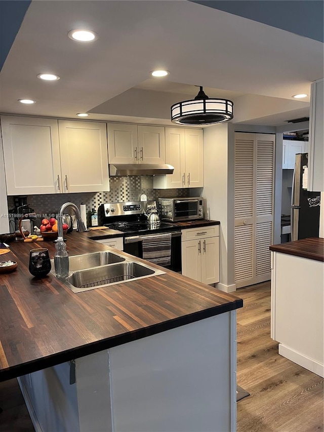 kitchen featuring light hardwood / wood-style floors, stainless steel appliances, tasteful backsplash, white cabinetry, and wooden counters