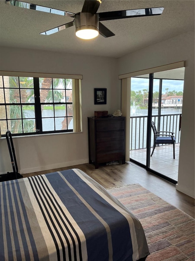 unfurnished bedroom with wood-type flooring, ceiling fan, a textured ceiling, and access to outside