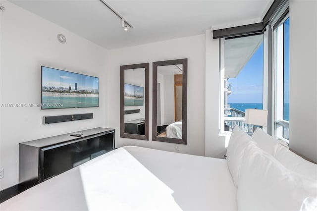 bedroom with track lighting and a water view